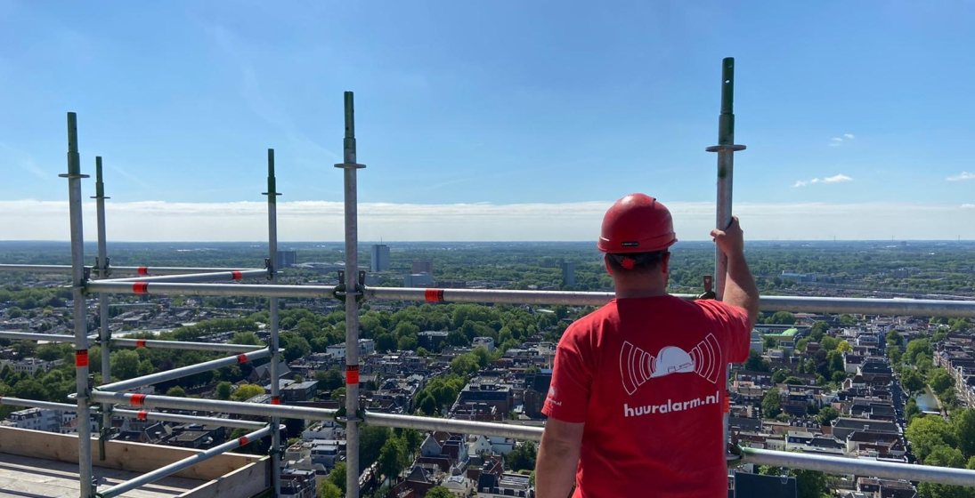 Huuralarm monteur op het dak van een gebouw